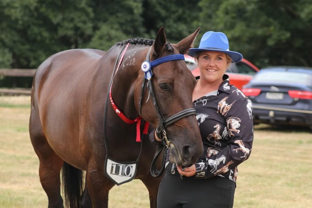 Handler with a plaited dark bay Standardbred in the in-hand ring